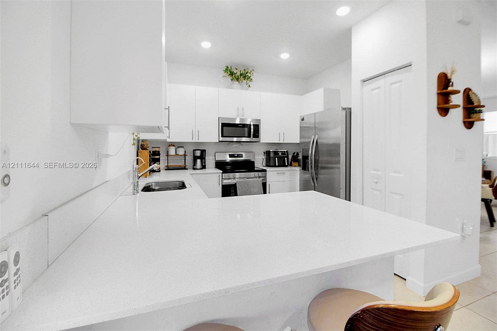 2873 SE 24th Avenue, Homestead, FL 33035 Kitchen featuring white shaker-style cabinetry, a solid-surface breakfast bar, stainless steel appliances, and recessed lighting