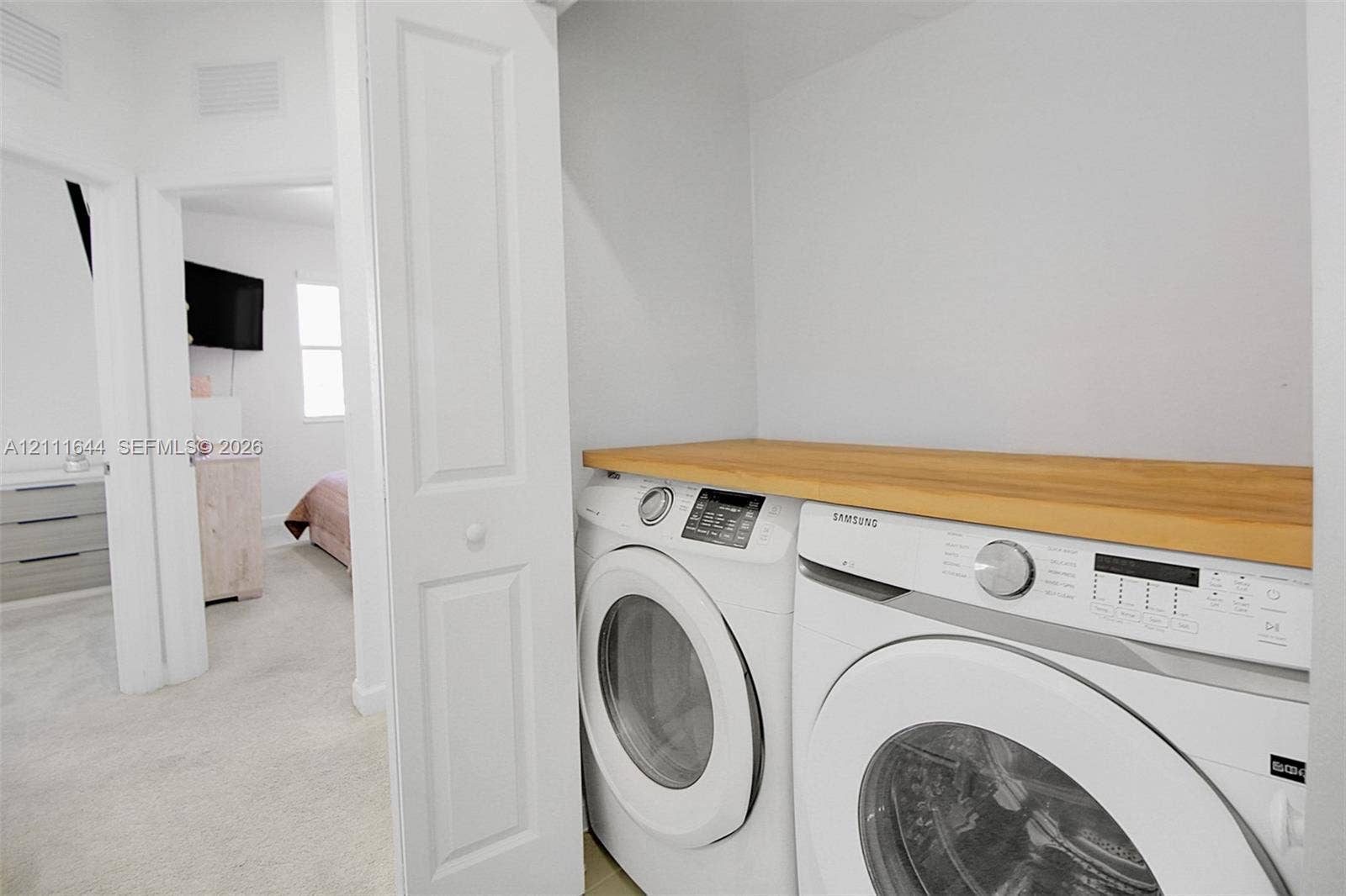 2873 SE 24th Avenue, Homestead, FL 33035 Laundry closet featuring stacked front-loading appliances and a built-in wood-finish folding counter