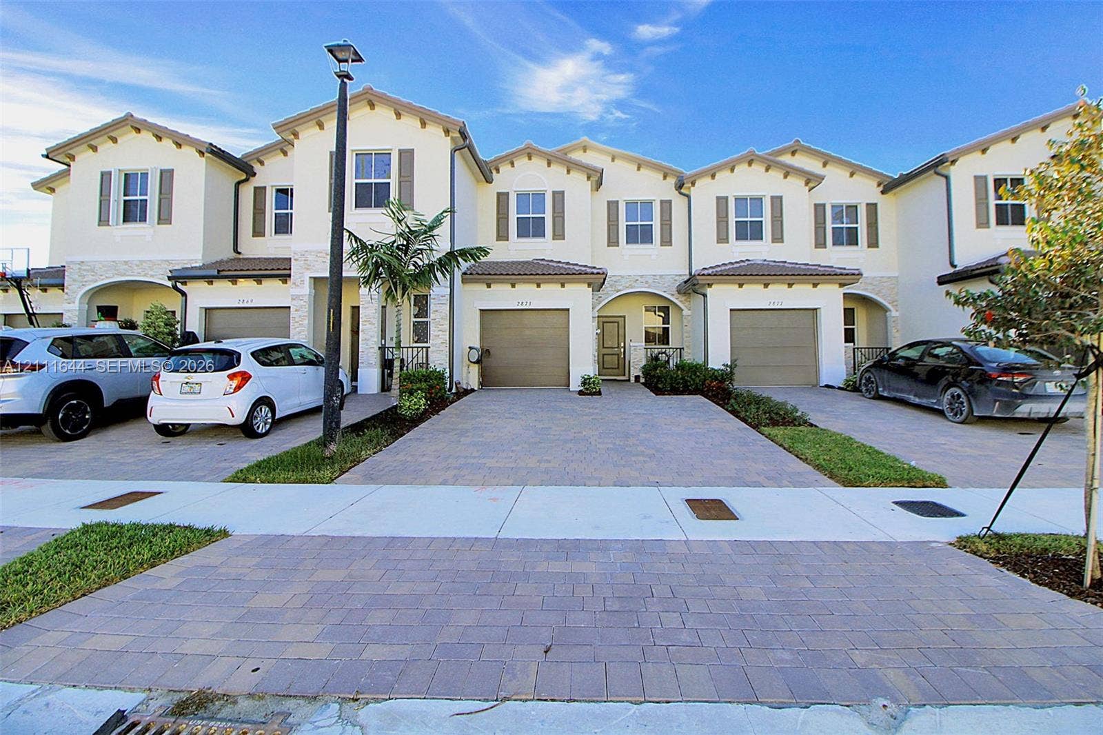 2873 SE 24th Avenue, Homestead, FL 33035 Multi-story townhome exterior featuring stucco facade, stone veneer accents, multi-gabled roofline, and paver driveways