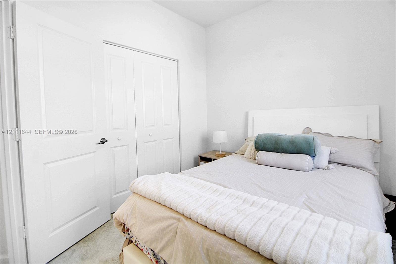 2873 SE 24th Avenue, Homestead, FL 33035 Neutral-toned interior featuring crisp white walls, a dual-panel closet with brushed nickel hardware, and high-pile wall-to-wall carpeting