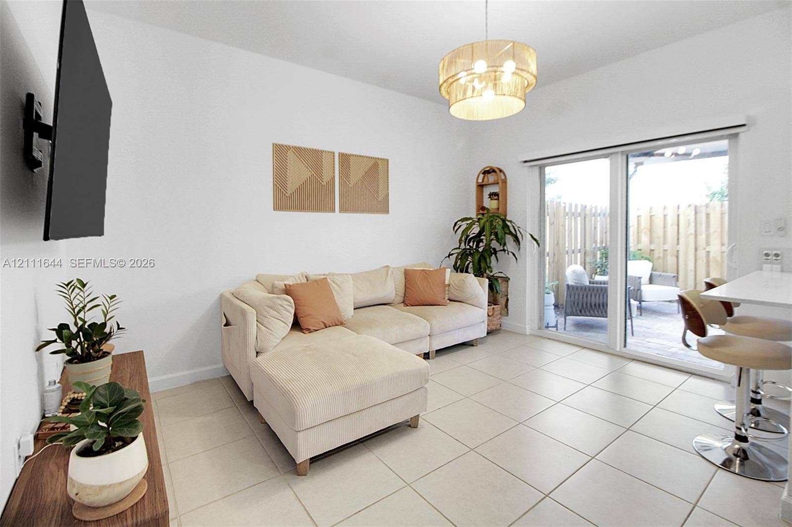 2873 SE 24th Avenue, Homestead, FL 33035 Neutral tile flooring, tiered drum pendant lighting, and a large sliding glass door featuring integrated patio access