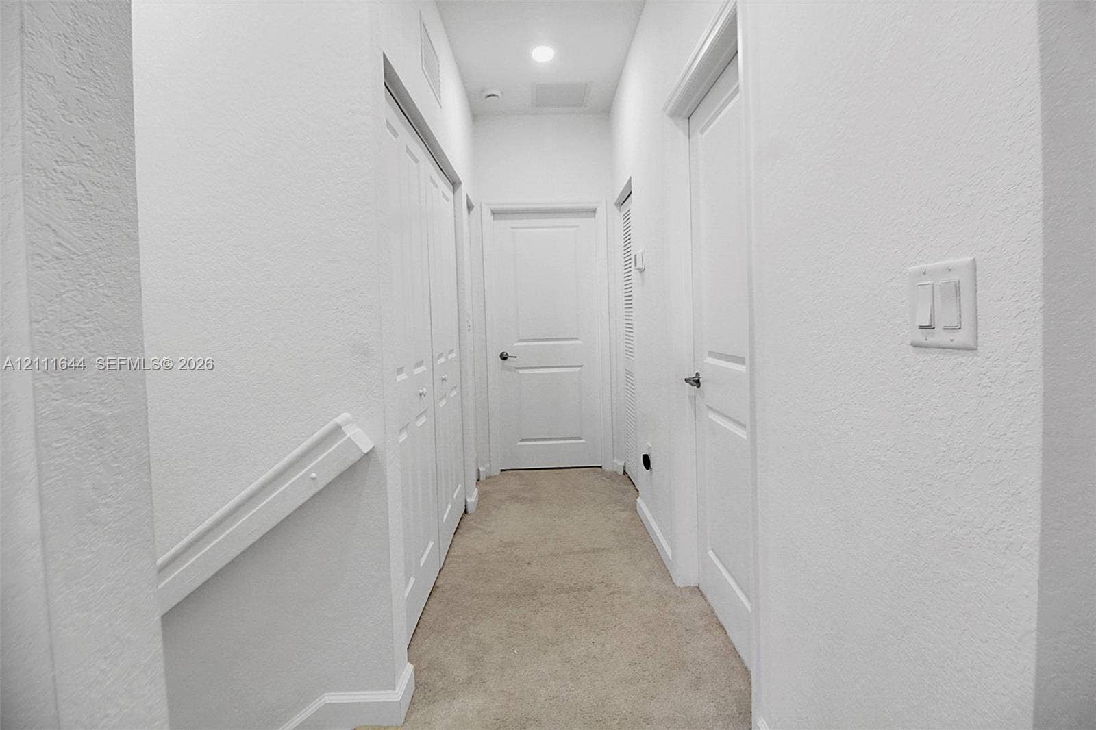2873 SE 24th Avenue, Homestead, FL 33035 Hallway featuring neutral wall-to-wall carpeting, three paneled interior doors, a double-door closet, and recessed ceiling lighting