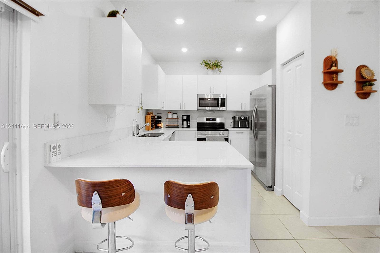 2873 SE 24th Avenue, Homestead, FL 33035 Kitchen featuring white cabinetry, solid-surface countertops with a breakfast bar, recessed ceiling lighting, and stainless-steel appliances