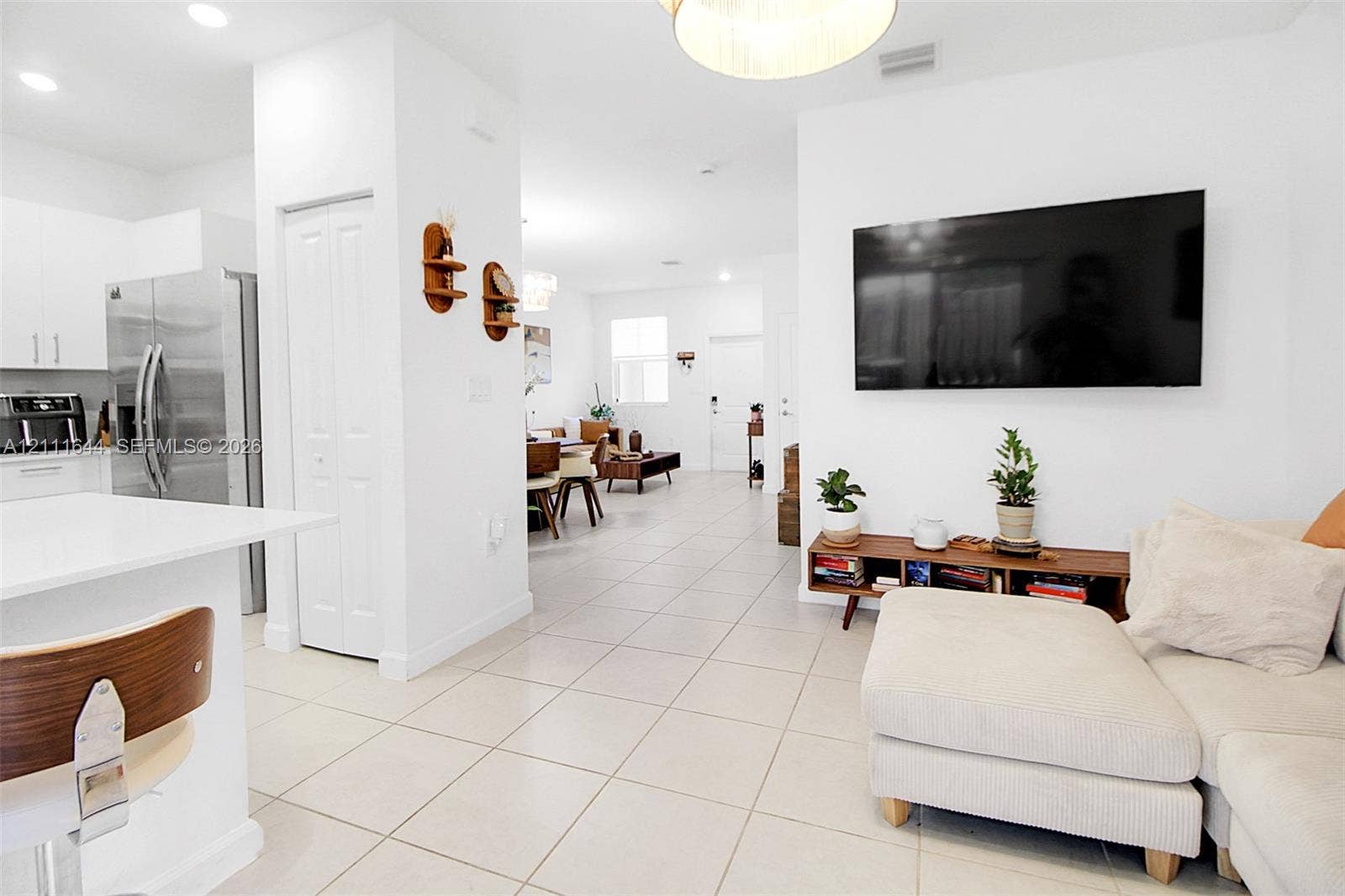 2873 SE 24th Avenue, Homestead, FL 33035 Open-concept floor plan featuring large-format tile flooring, white cabinetry, integrated stainless steel appliances, and recessed lighting