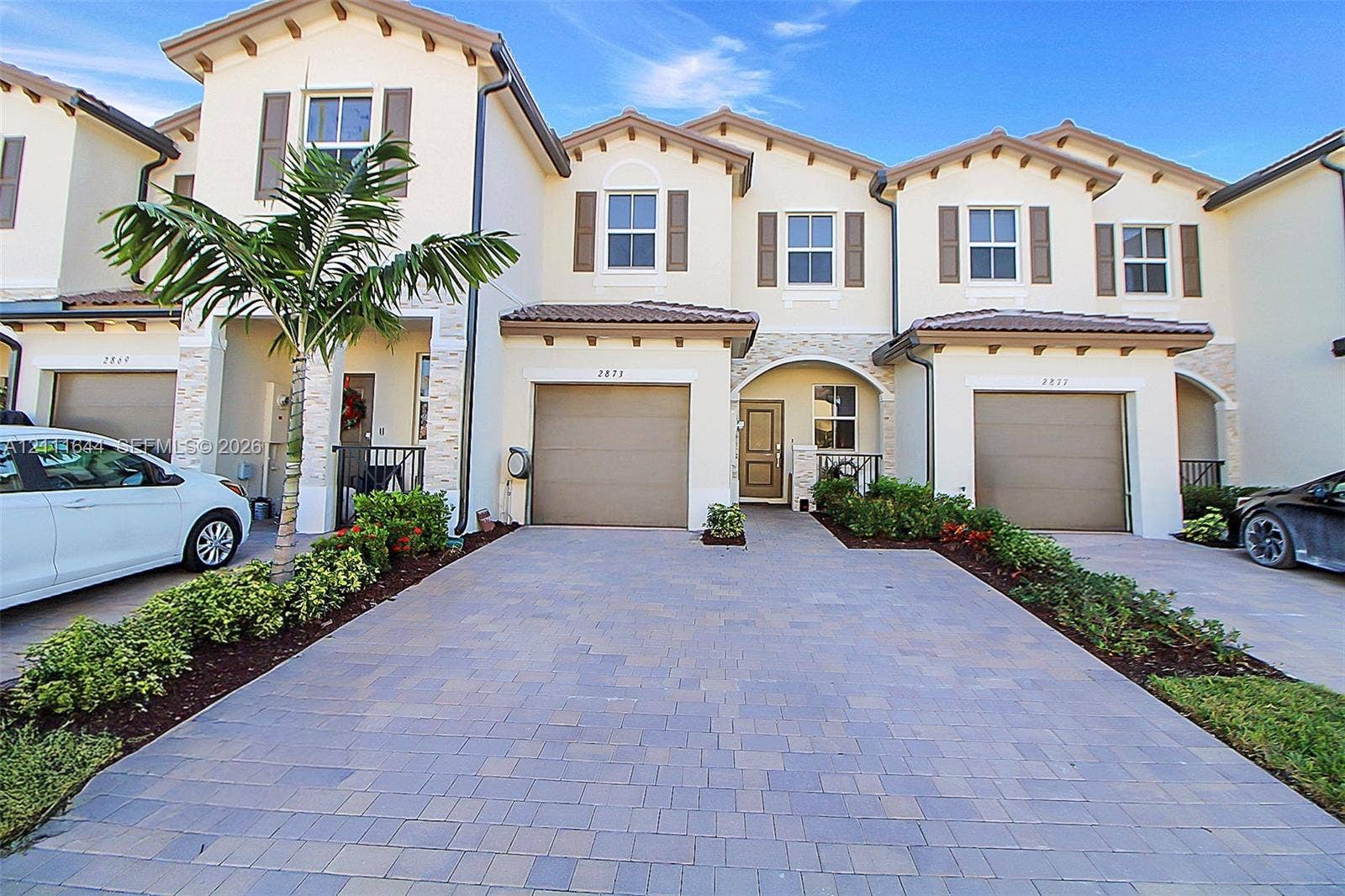 2873 SE 24th Avenue, Homestead, FL 33035 Mediterranean-style exterior featuring stucco siding, stone veneer accents, paver driveway, attached multi-car garages, and recessed entryways