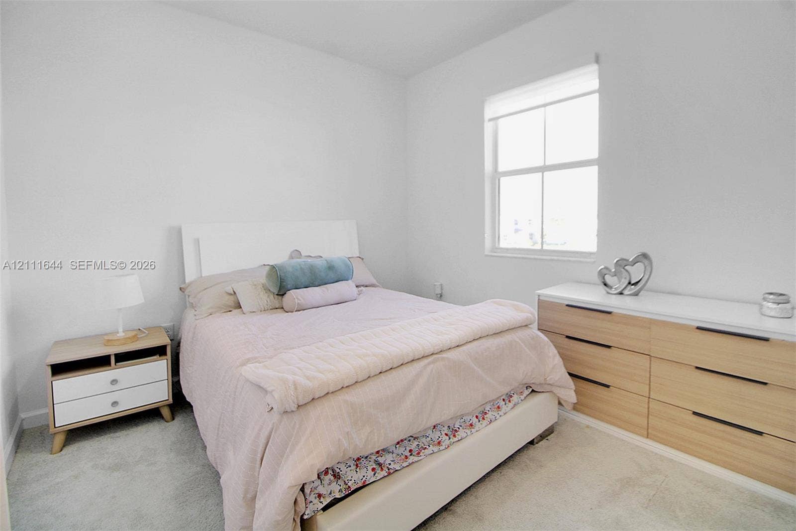 2873 SE 24th Avenue, Homestead, FL 33035 Neutral-toned interior space featuring light-colored wall-to-wall carpeting and a single-pane window with a roller shade