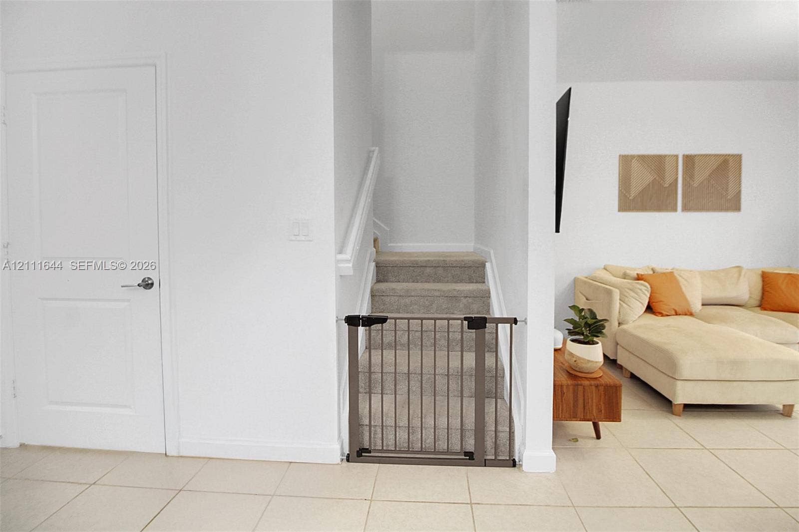 2873 SE 24th Avenue, Homestead, FL 33035 Neutral-toned ceramic tile flooring, staircase with carpeted treads, and painted white interior doors with satin nickel hardware