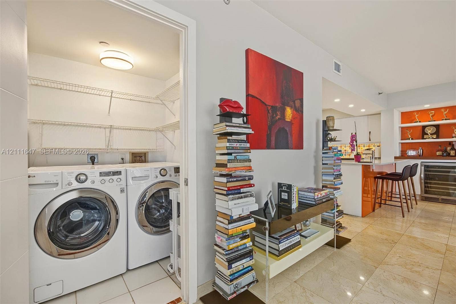 8925 Collins Avenue, #4J, Surfside, FL 33154 Dedicated laundry closet featuring built-in wire shelving and tile flooring, accompanied by kitchen cabinetry with a breakfast bar, under-cabinet lighting, and recessed shelving