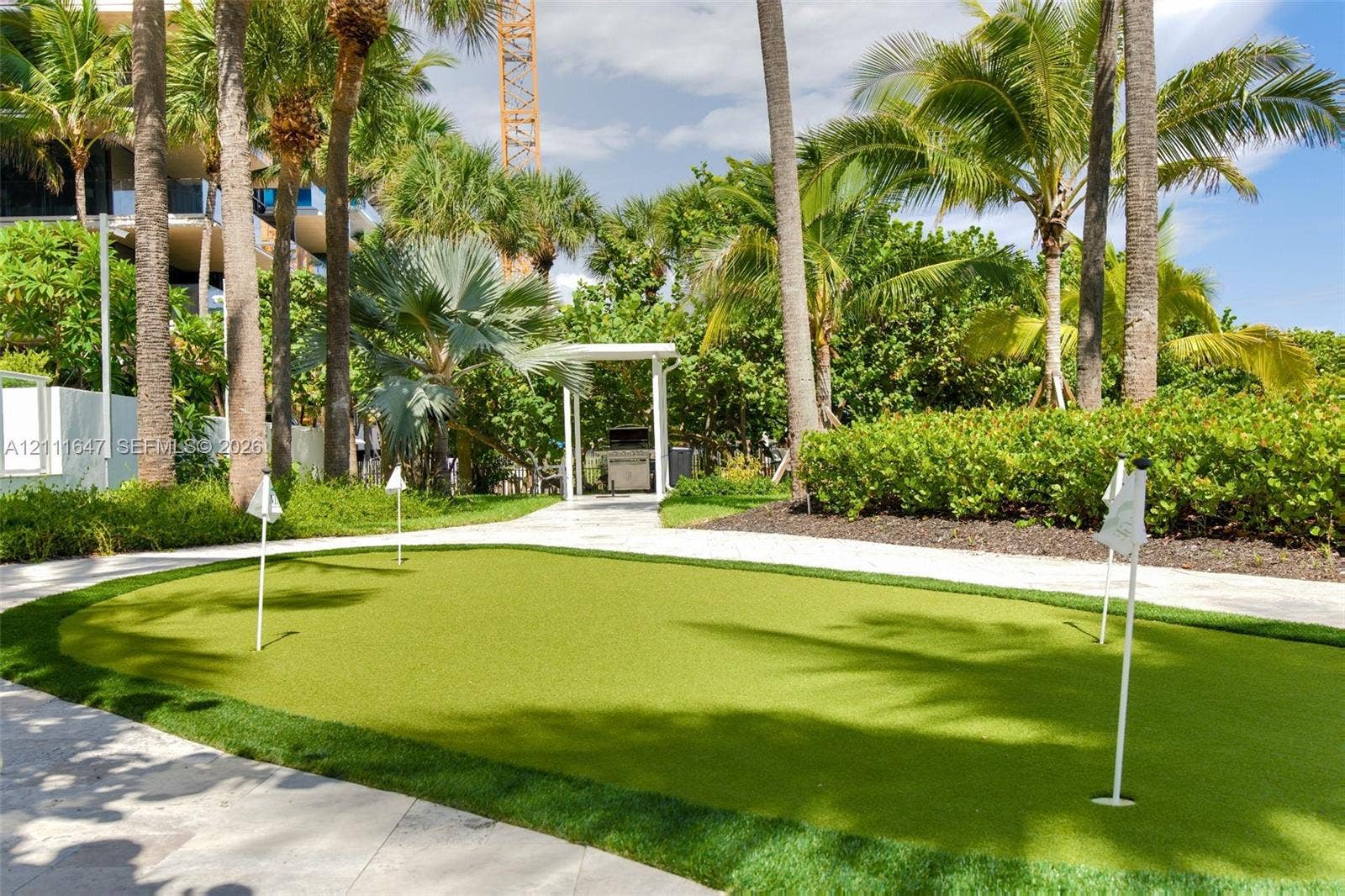 8925 Collins Avenue, #4J, Surfside, FL 33154 Putting green with synthetic turf surfacing, stone-paved walkways, and established palm trees
