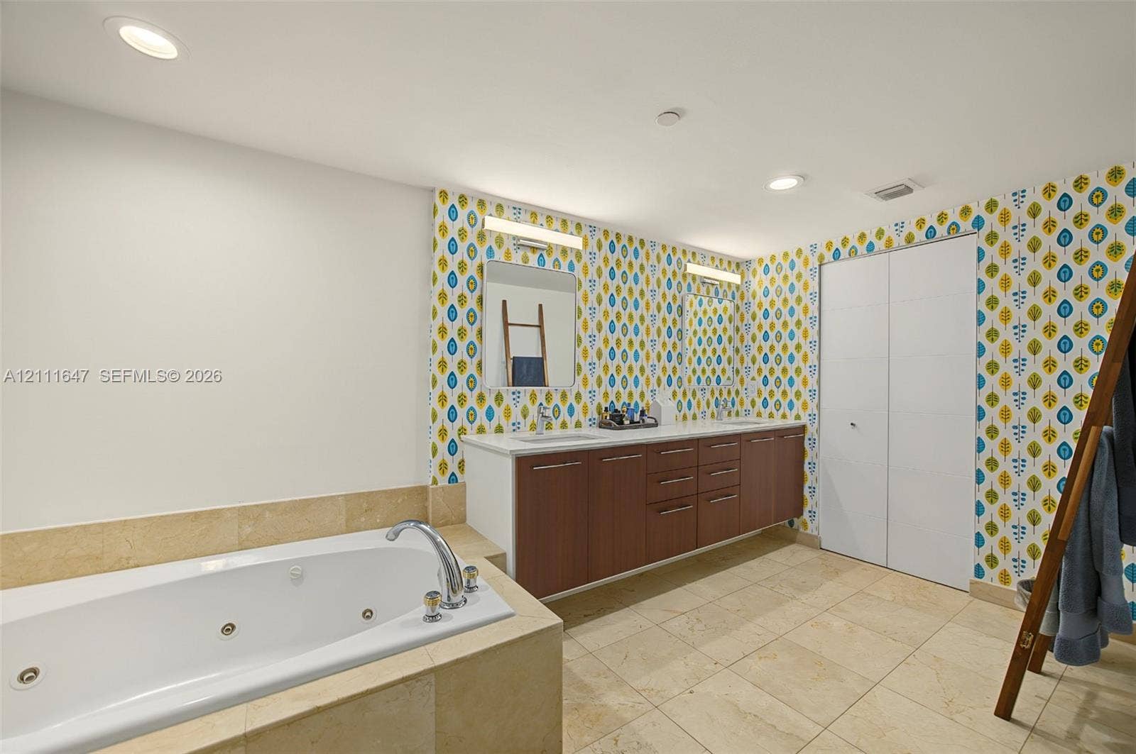 8925 Collins Avenue, #4J, Surfside, FL 33154 Jetted soaking tub with tile surround, dual-sink vanity with wood-finish cabinetry, stone tile flooring, and integrated wall lighting