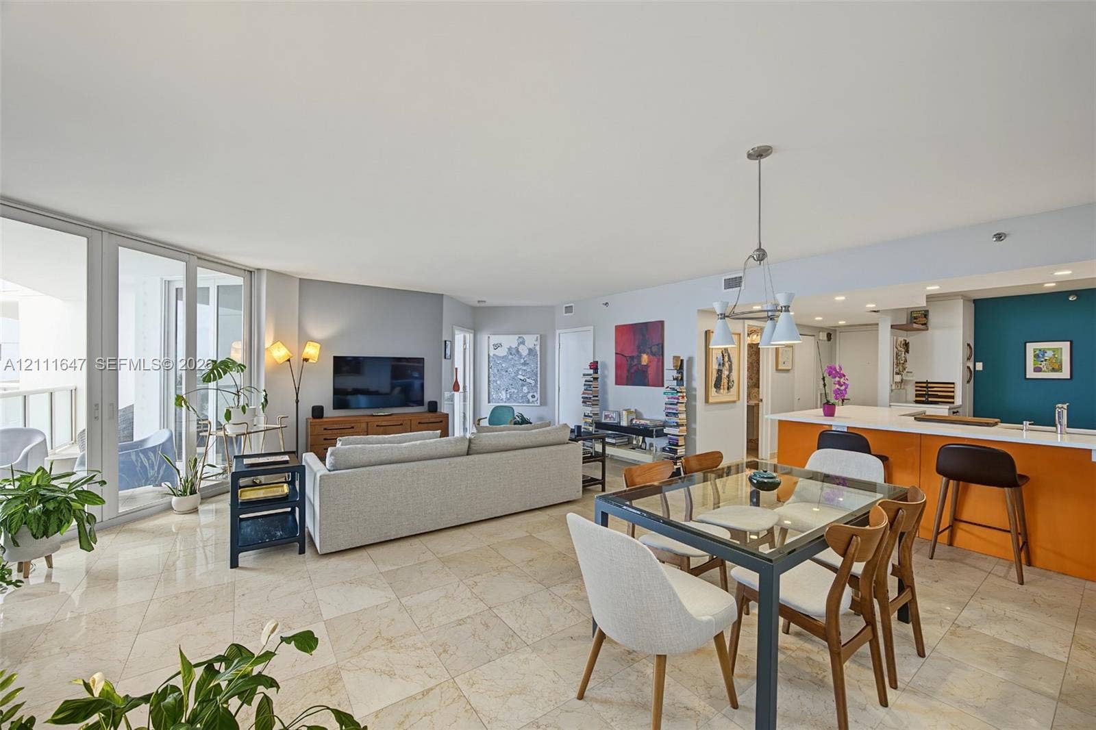 8925 Collins Avenue, #4J, Surfside, FL 33154 Open-concept interior featuring light-toned tile flooring, floor-to-ceiling glass sliding doors, recessed lighting, a built-in kitchen peninsula, and a multi-pendant light fixture