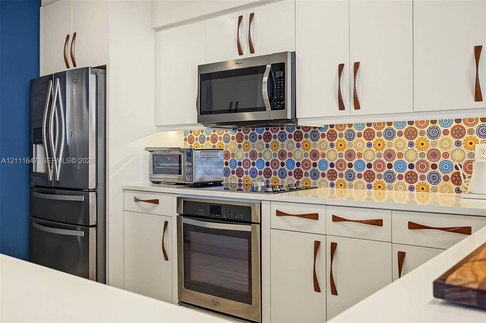 8925 Collins Avenue, #4J, Surfside, FL 33154 Kitchen featuring white cabinetry with wood-finish hardware, patterned tile backsplash, quartz countertops, and stainless steel appliances