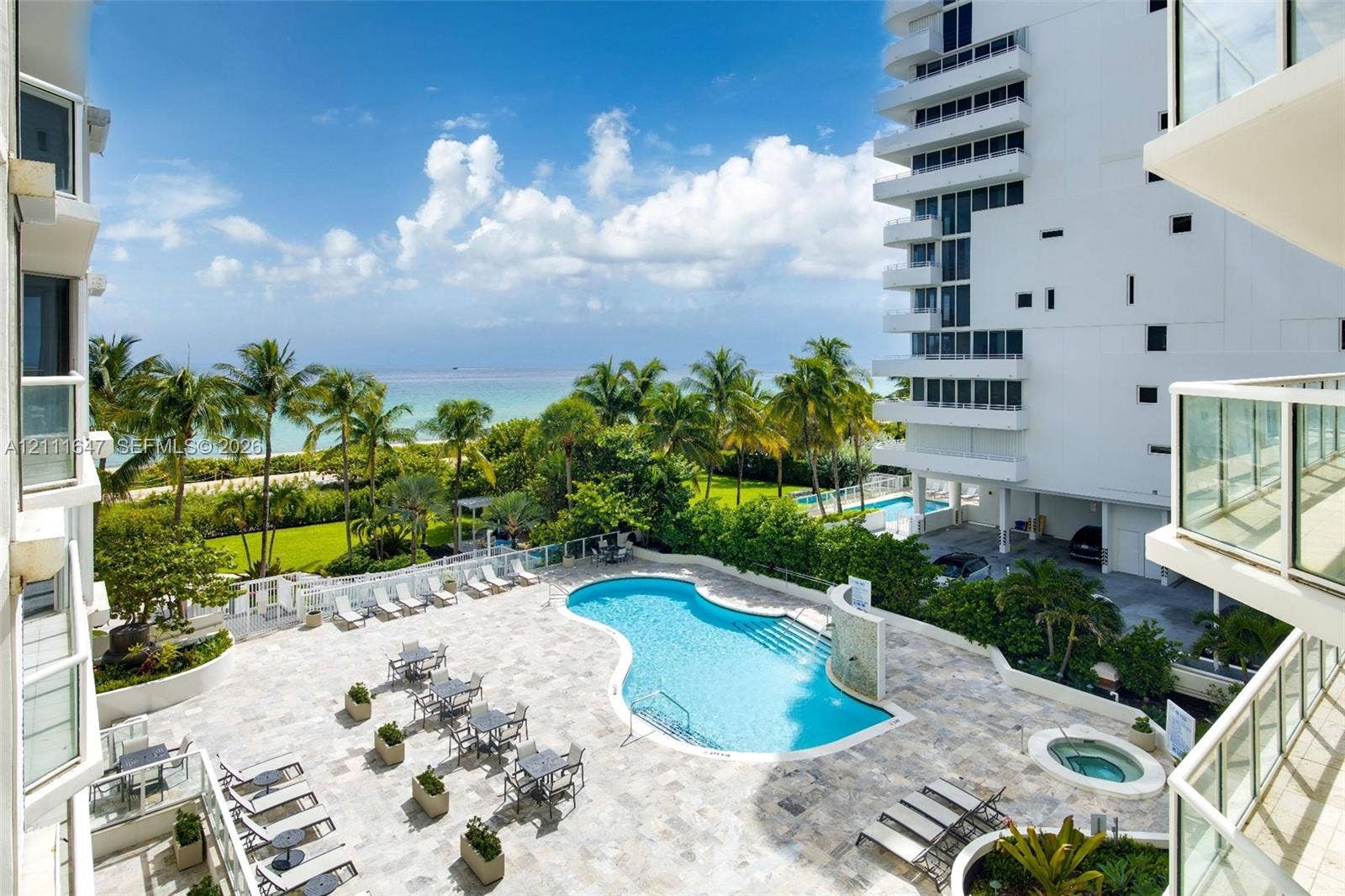 8925 Collins Avenue, #4J, Surfside, FL 33154 Outdoor swimming pool and spa surrounded by a stone-paved deck, landscaped grounds, and ocean scenery