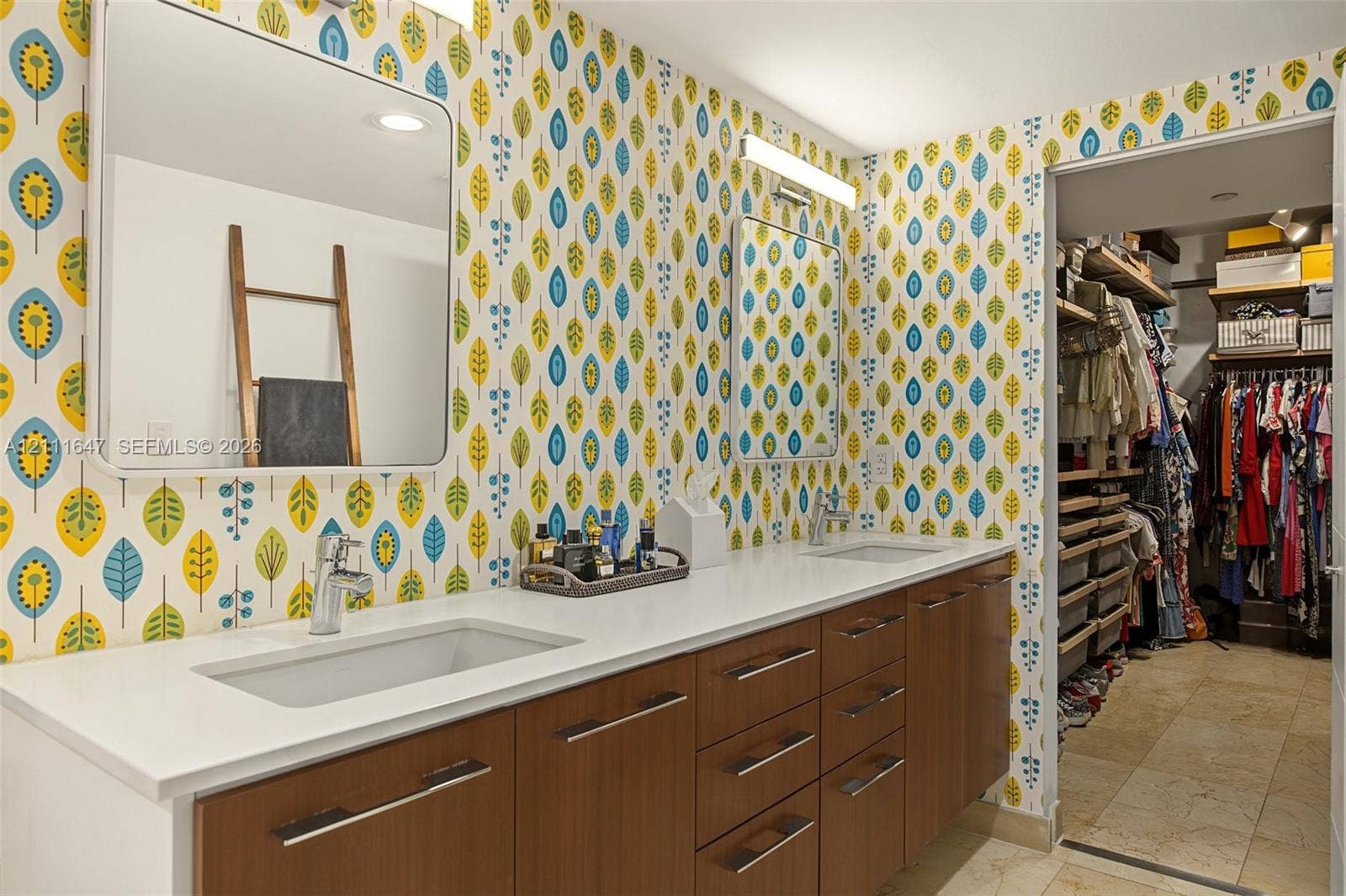 8925 Collins Avenue, #4J, Surfside, FL 33154 Dual-vanity cabinetry with wood-finish drawer fronts, rectangular undermount sinks, stone countertops, and wall-mounted light fixtures