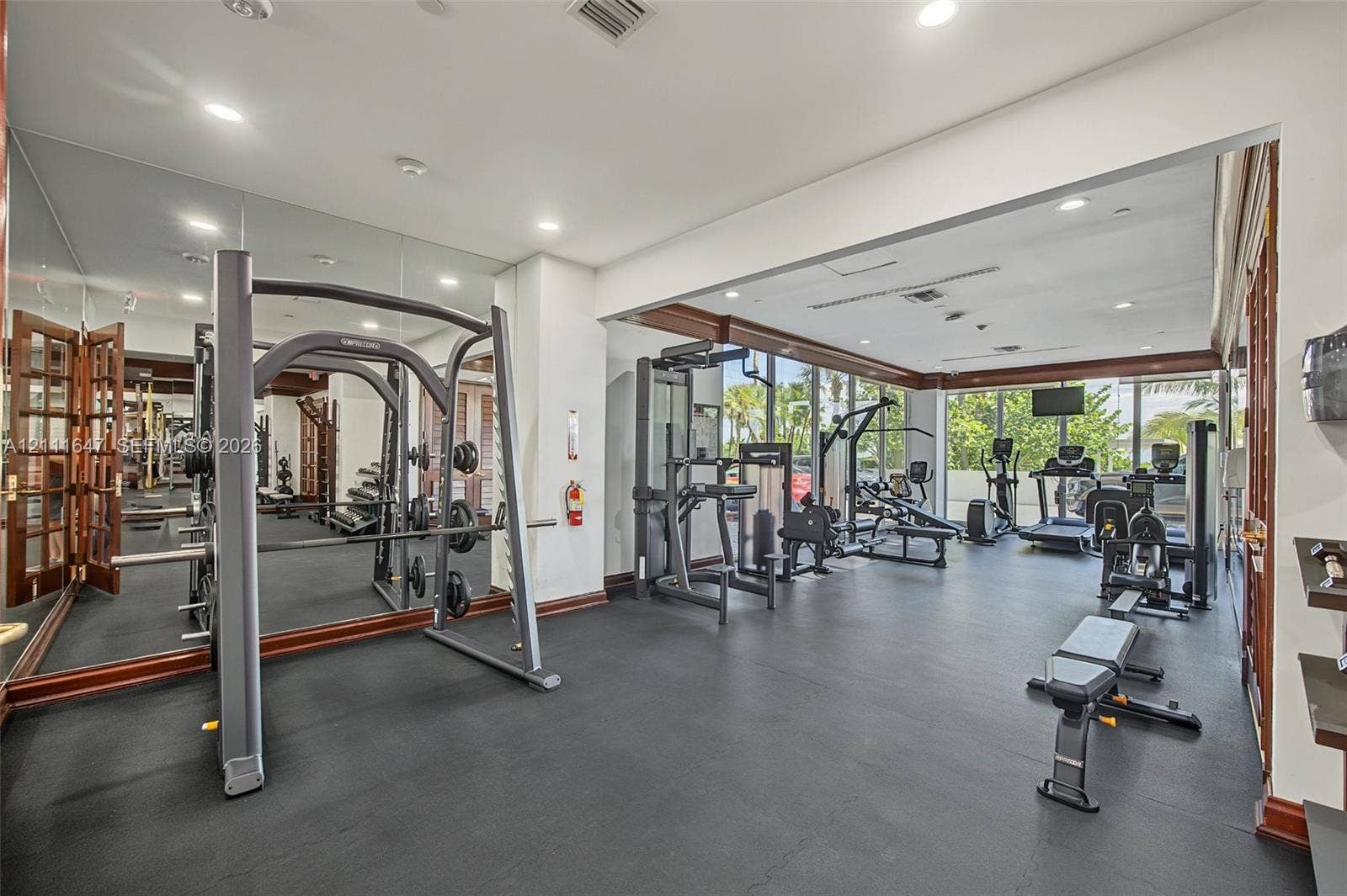 8925 Collins Avenue, #4J, Surfside, FL 33154 Fitness room featuring wall-to-wall mirrors, expansive floor-to-ceiling windows, recessed lighting, and durable rubber flooring with dark wood-finish trim