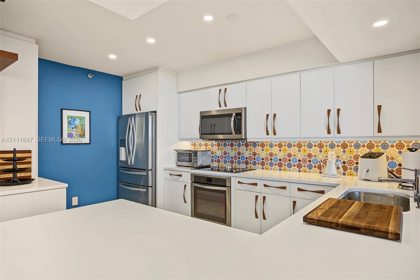 8925 Collins Avenue, #4J, Surfside, FL 33154 Kitchen featuring white cabinetry with integrated hardware, patterned tile backsplash, quartz countertops, stainless steel appliances, and recessed lighting