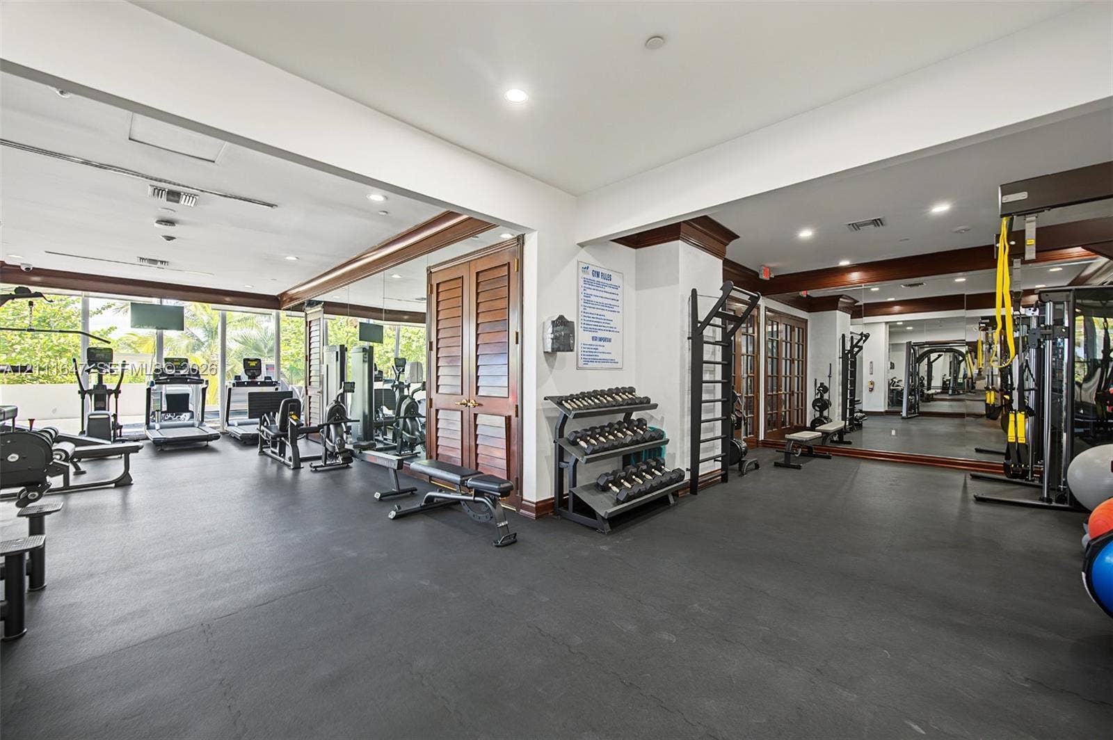 8925 Collins Avenue, #4J, Surfside, FL 33154 Fitness center featuring high-impact rubber flooring, expansive wall-to-wall mirrors, recessed lighting, and wood-finish louvered door detailing