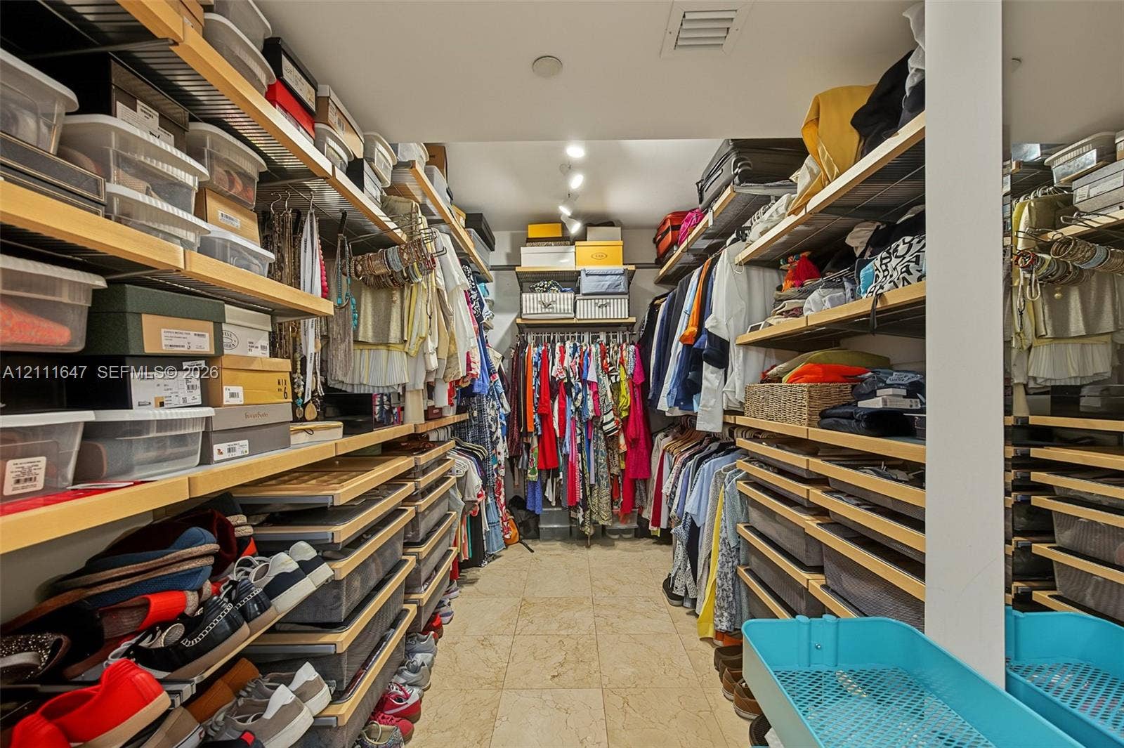 8925 Collins Avenue, #4J, Surfside, FL 33154 Walk-in closet featuring extensive custom wood shelving, integrated hanging rods, recessed ceiling lighting, and stone flooring