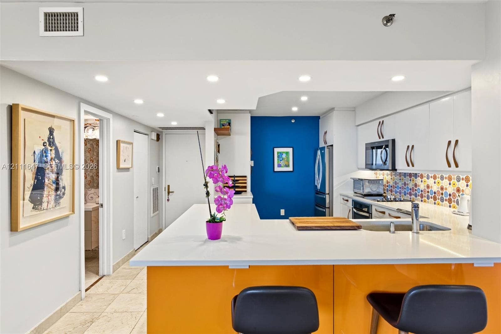 8925 Collins Avenue, #4J, Surfside, FL 33154 Kitchen featuring a peninsula with quartz countertop, white cabinetry, white upper cabinets, stainless steel appliances, and a multicolor patterned backsplash