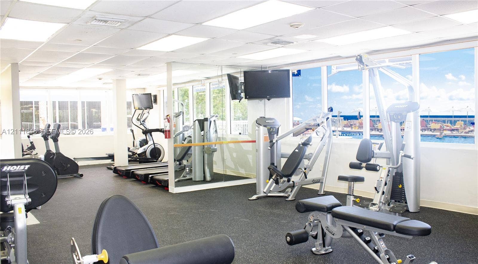 19201 Collins Avenue, #518, Sunny Isles Beach, FL 33160 Fitness center featuring rubber flooring, expansive floor-to-ceiling windows, mirror-paneled walls, and recessed grid lighting
