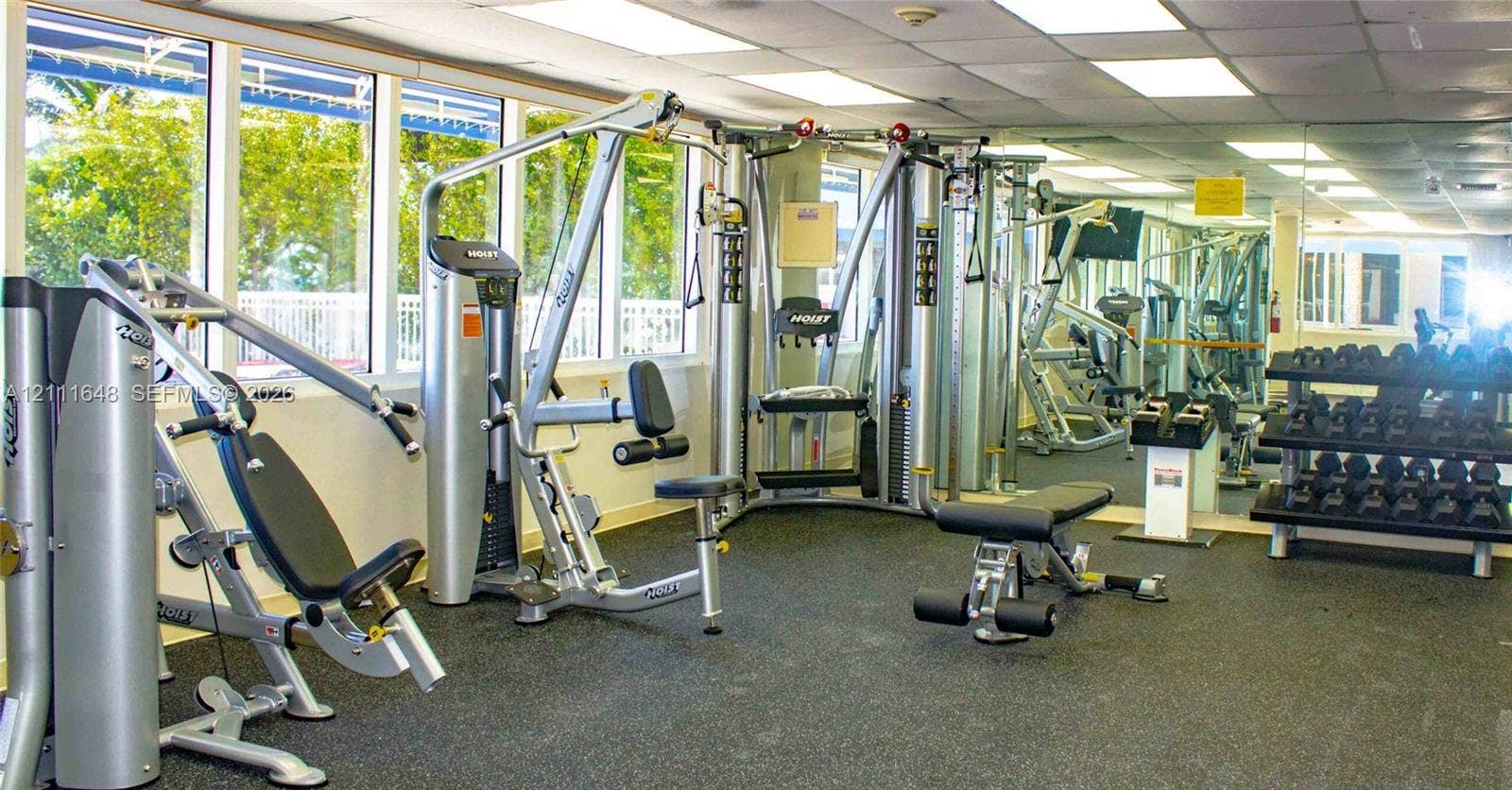 19201 Collins Avenue, #518, Sunny Isles Beach, FL 33160 Fitness center featuring a wall of floor-to-ceiling mirrors, large windows with natural lighting, and rubberized flooring