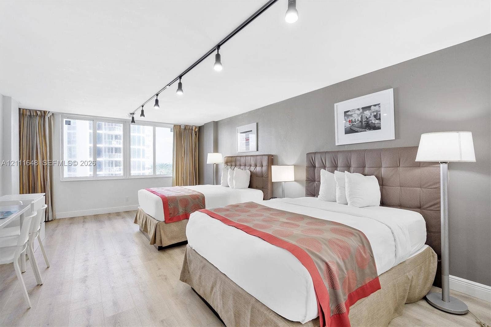 19201 Collins Avenue, #518, Sunny Isles Beach, FL 33160 Expansive room featuring wood-finish flooring, neutral gray accent walls, and large windows with integrated track lighting
