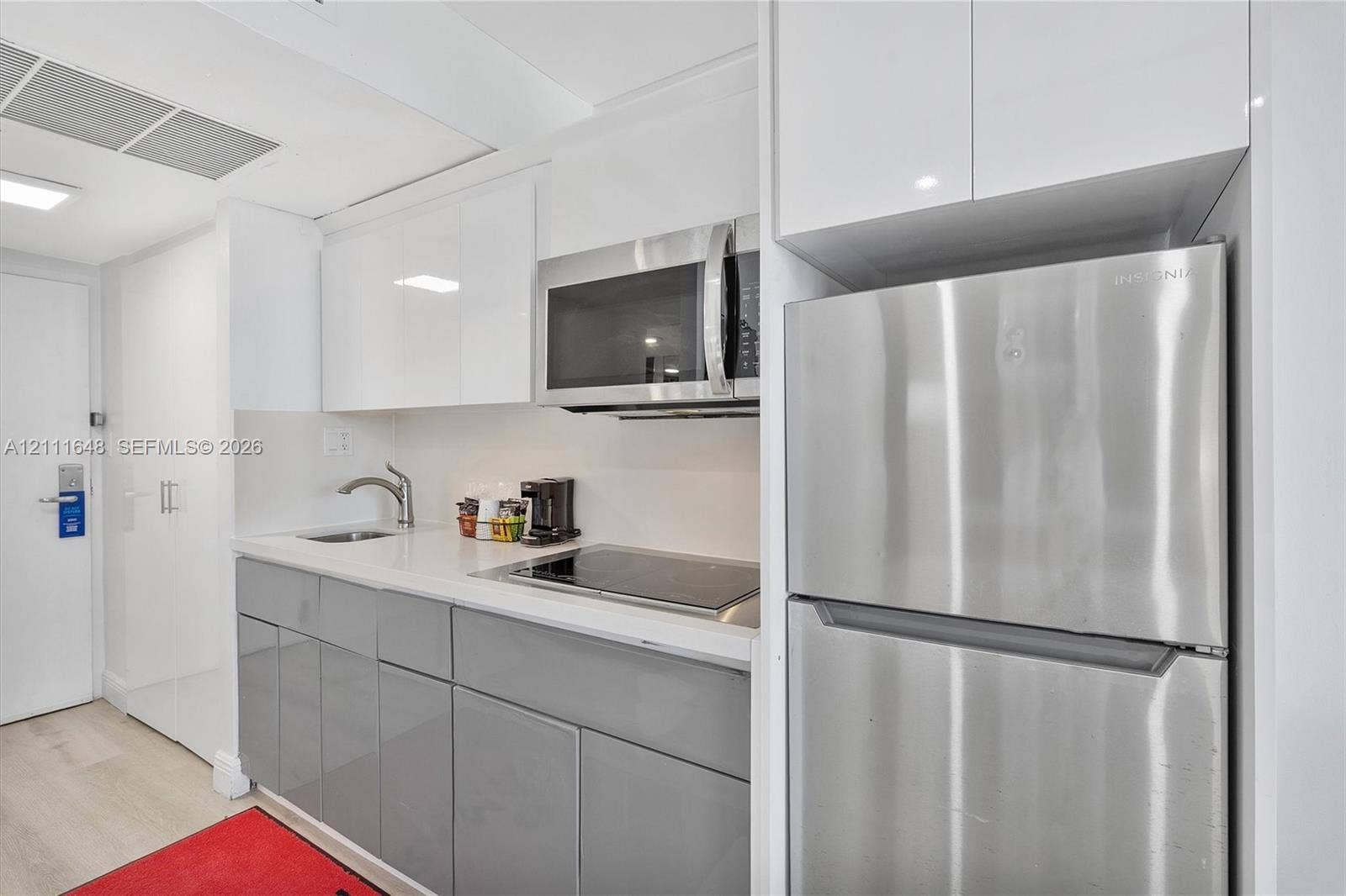 19201 Collins Avenue, #518, Sunny Isles Beach, FL 33160 Kitchen featuring high-gloss white upper cabinetry, grey lower cabinetry, stainless steel refrigerator, built-in microwave, and integrated cooktop