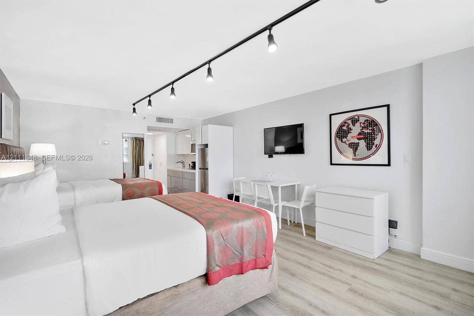 19201 Collins Avenue, #518, Sunny Isles Beach, FL 33160 Light-toned wood-finish flooring, linear track lighting, and a kitchenette featuring white cabinetry and grey countertops