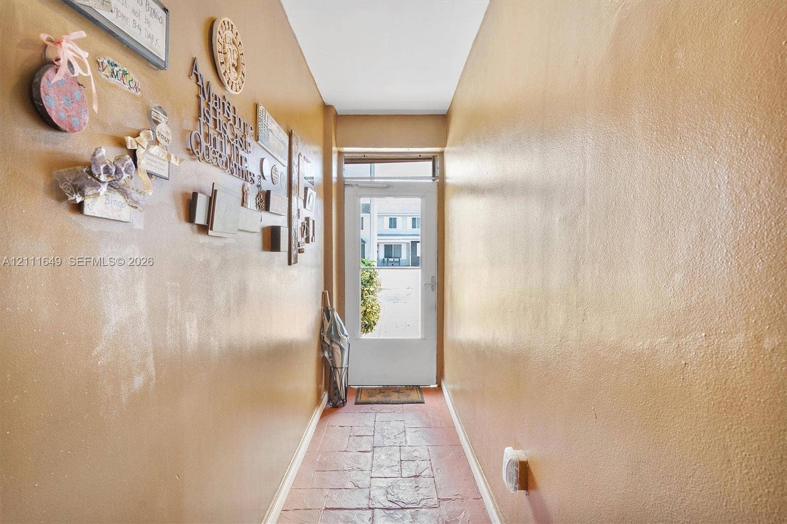 Entryway featuring textured stone-style tile flooring and a glass-paneled exterior door with an overhead transom window