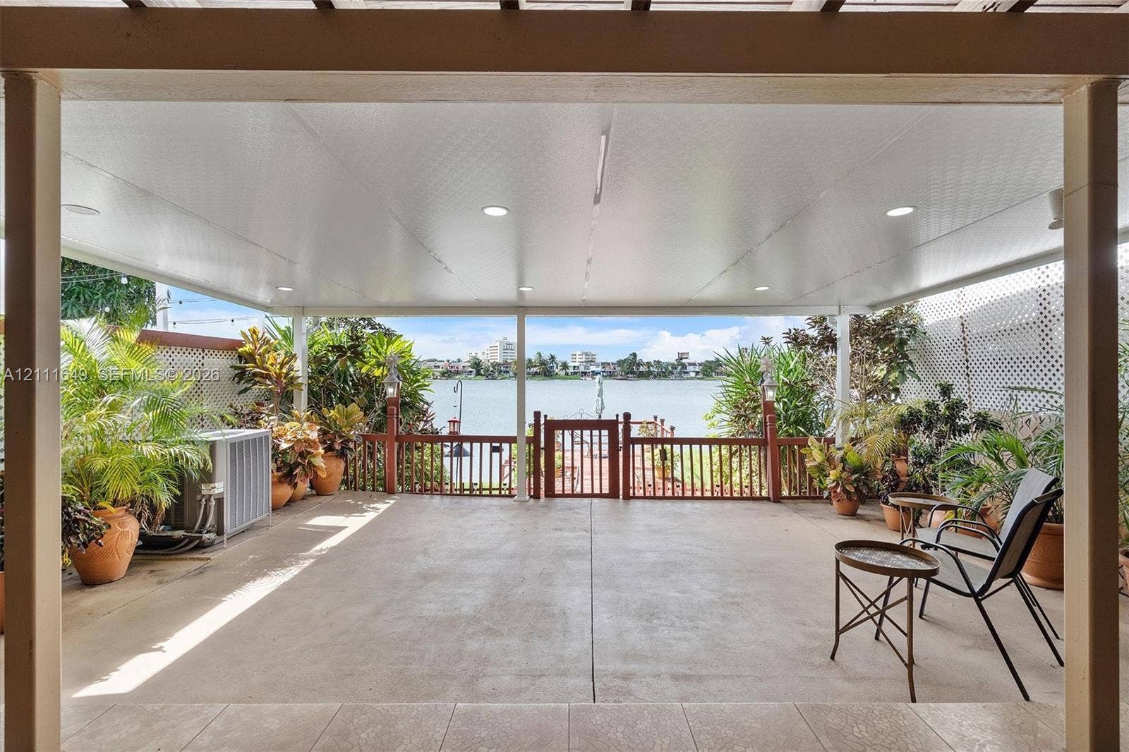 Covered patio featuring concrete flooring, recessed lighting, and a wood-slat railing with gated access