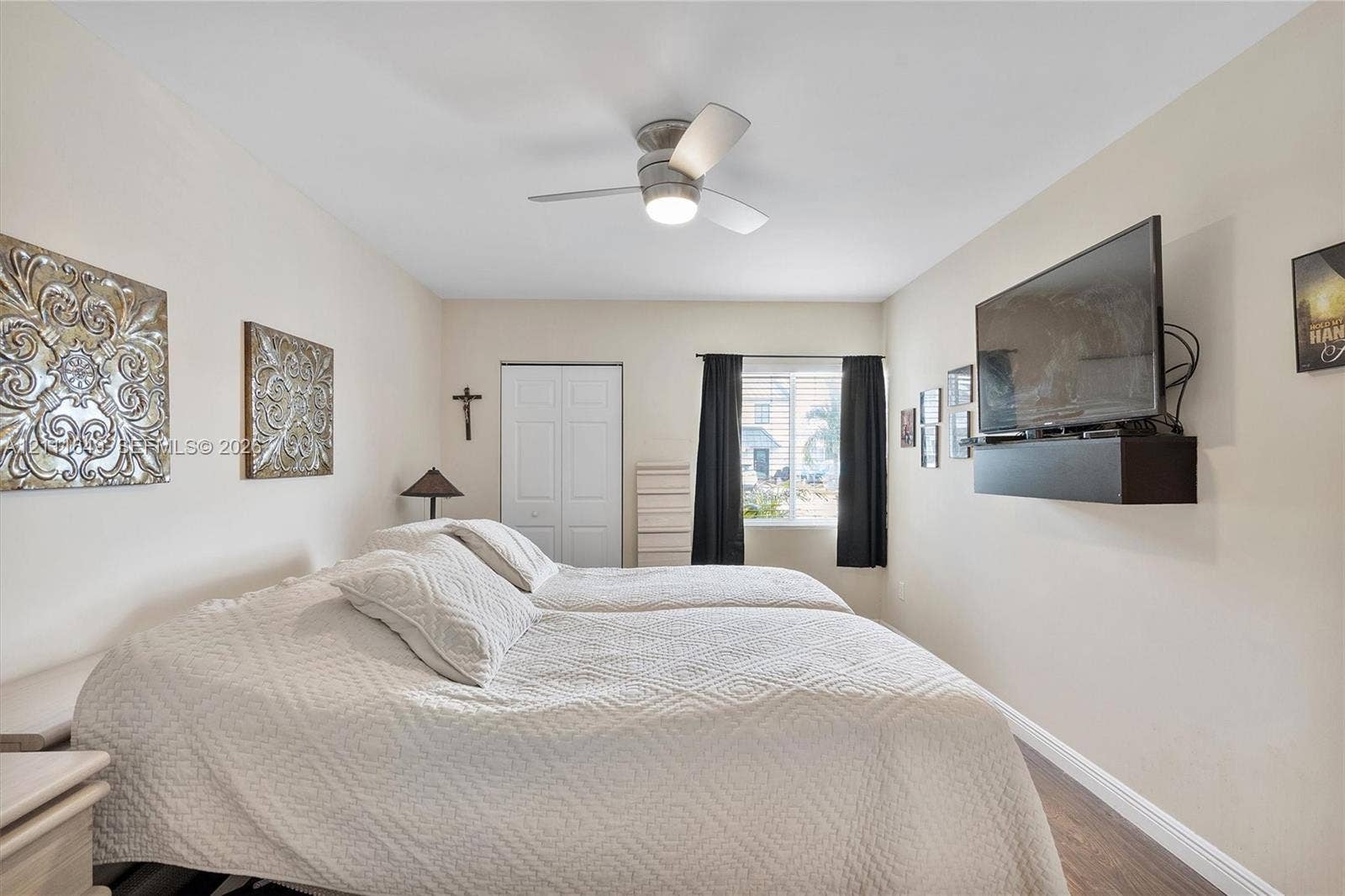Bedroom featuring wood-finish flooring, a ceiling fan with integrated lighting, and a dual-panel closet door