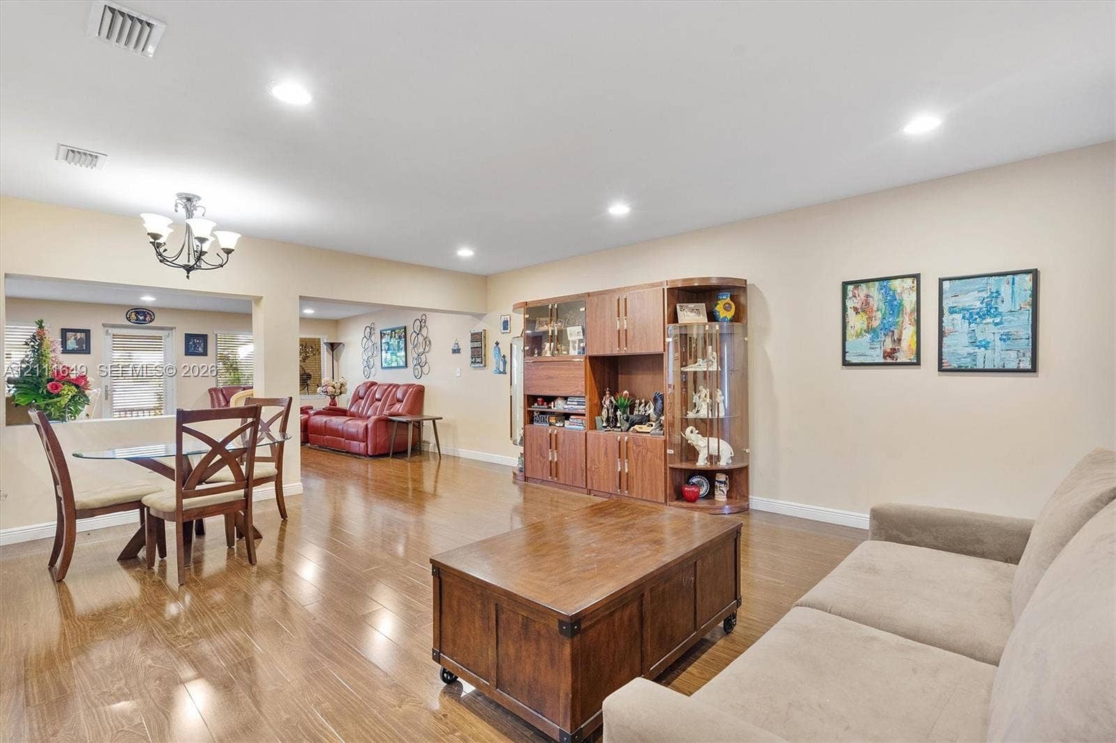 Open-concept interior featuring wood-finish flooring, recessed lighting, and built-in cabinetry with glass-front display shelving