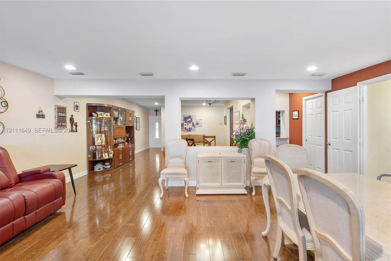 Open-concept floor plan featuring wood-finish flooring, recessed lighting, and built-in display cabinetry with glass shelving