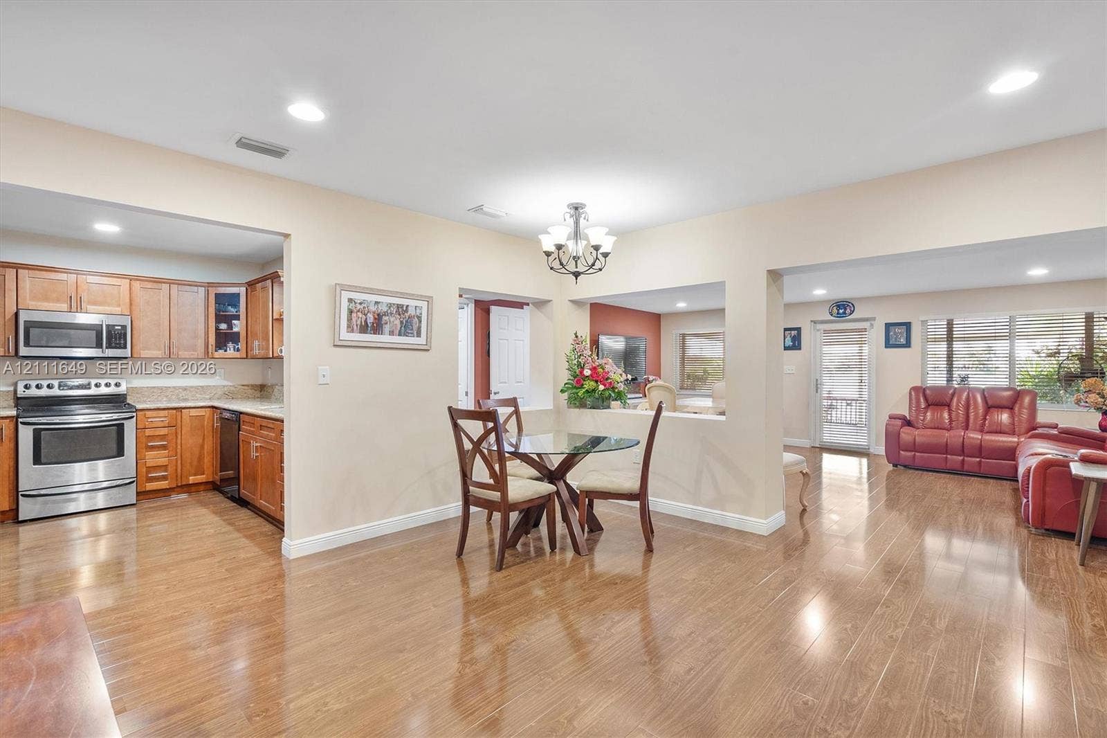Open-concept interior featuring wood-finish flooring, recessed lighting, and kitchen cabinetry with integrated stainless steel appliances