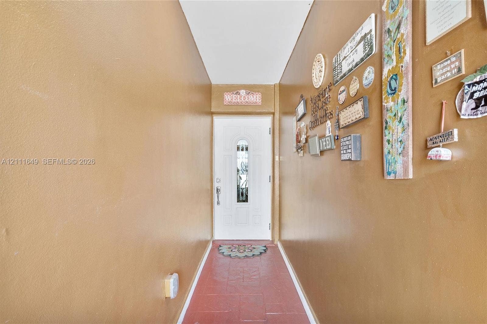 Entrance featuring a white exterior-style door with a decorative glass insert, metal hardware, and tiled flooring