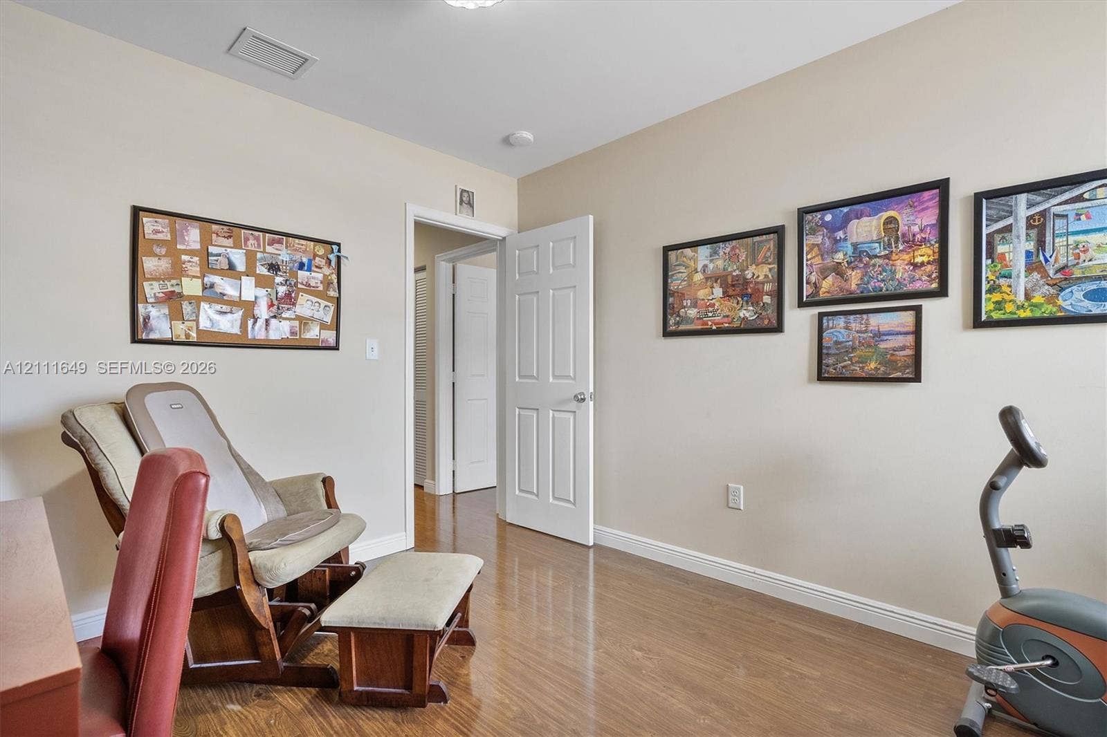 Room featuring wood-finish flooring and a six-panel interior door