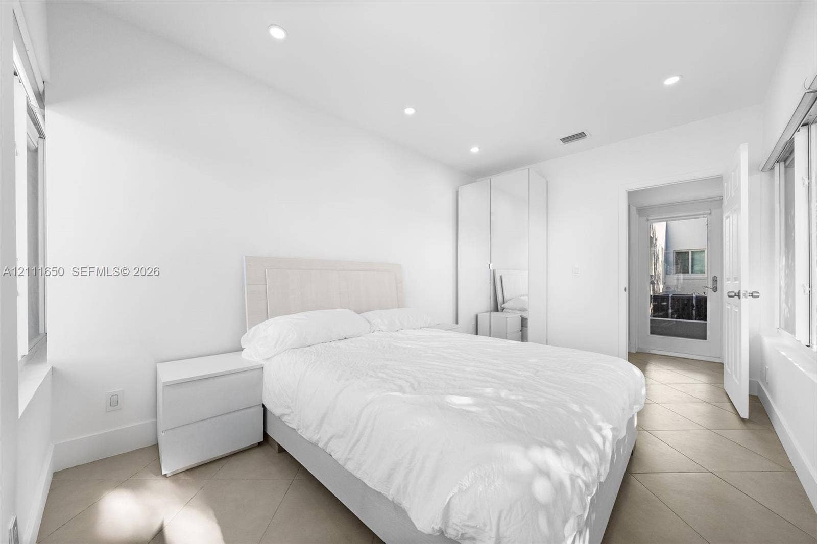 Neutral-toned tile flooring, recessed ceiling lighting, and floor-to-ceiling built-in cabinetry with mirrored panels