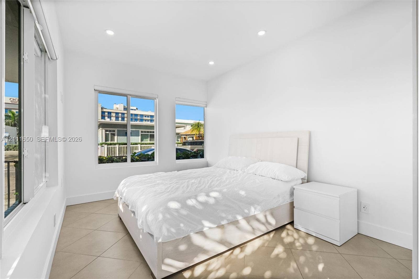 Neutral-toned tile flooring, recessed ceiling lighting, and multiple windows with integrated blinds