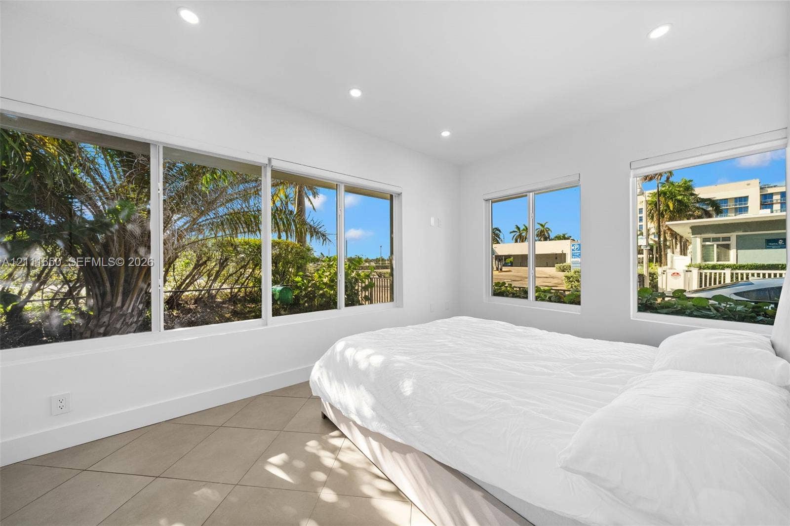Large-format windows, neutral tile flooring, and recessed ceiling lighting