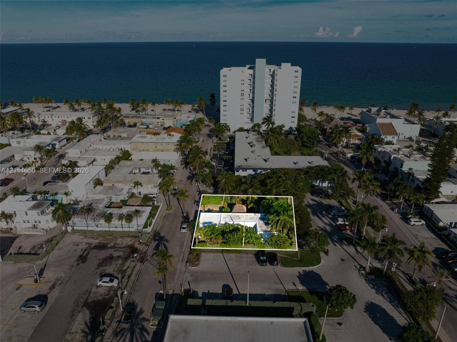 Aerial perspective featuring a flat-roofed structure situated on a corner lot with mature palms and foliage