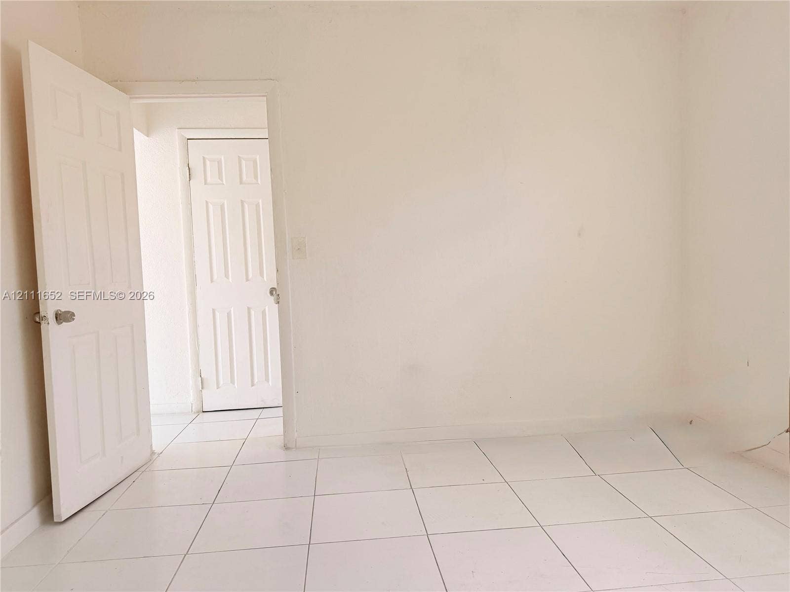 Interior space featuring white tile flooring and dual six-panel interior doors with metallic hardware