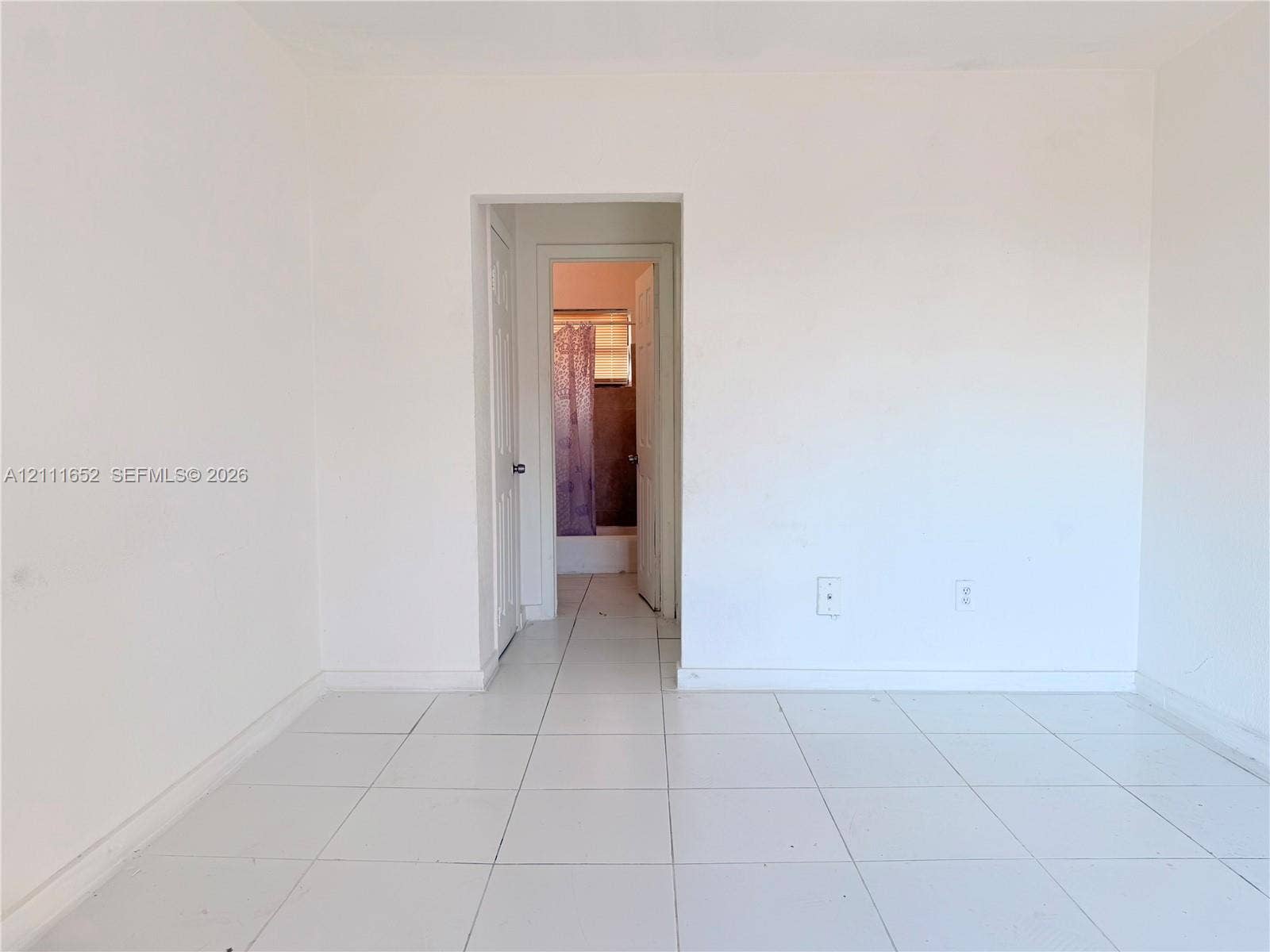 Neutral-toned interior space featuring white wall finishes and uniform tile flooring