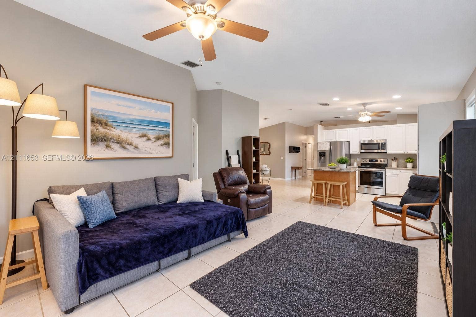 1042 NE 38th Street, Oakland Park, FL 33334 Open-concept interior featuring high vaulted ceilings, light-tone floor tiling, a kitchen island with stone countertops, and recessed lighting