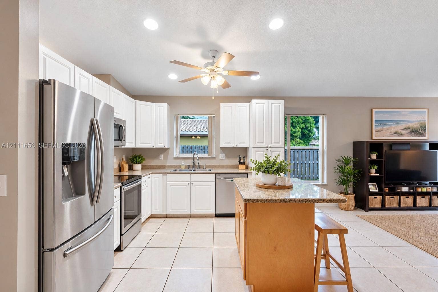 1042 NE 38th Street, Oakland Park, FL 33334 Kitchen featuring white shaker-style cabinetry, stone-finish countertops, stainless steel appliances, a center island, and tile flooring