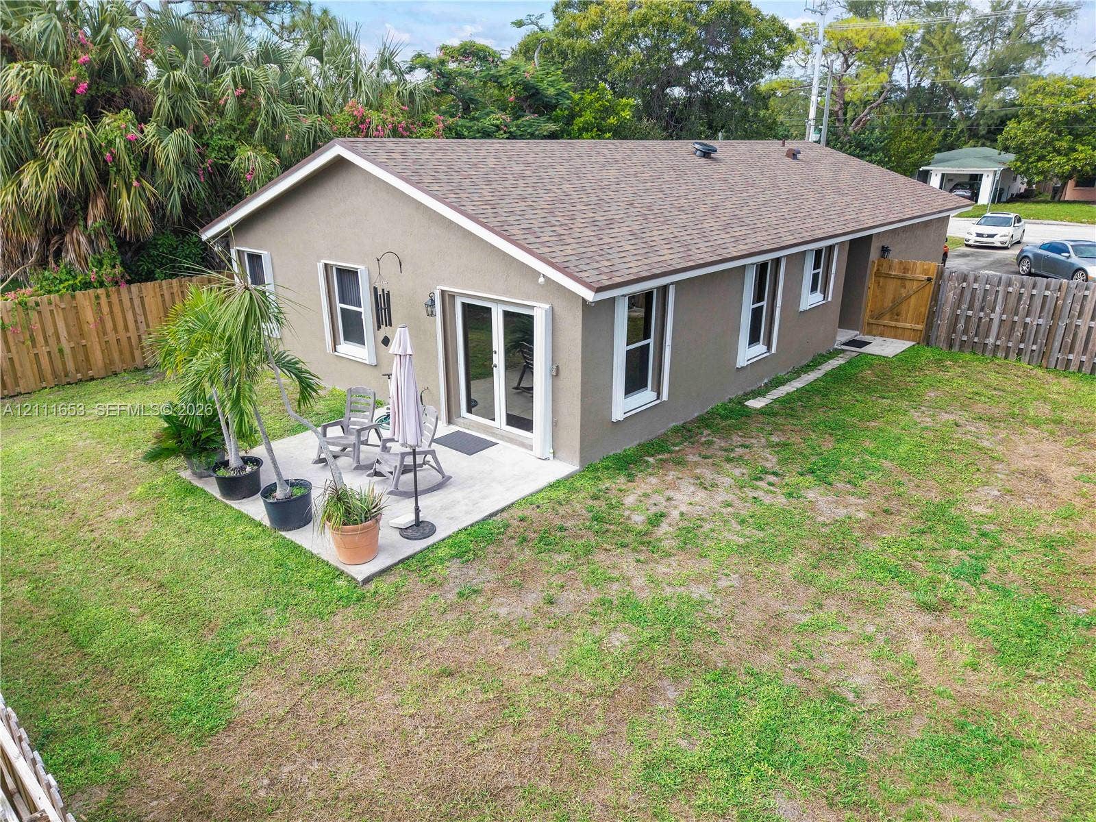 1042 NE 38th Street, Oakland Park, FL 33334 Paved backyard patio, double glass doors, and wood-panel perimeter fencing