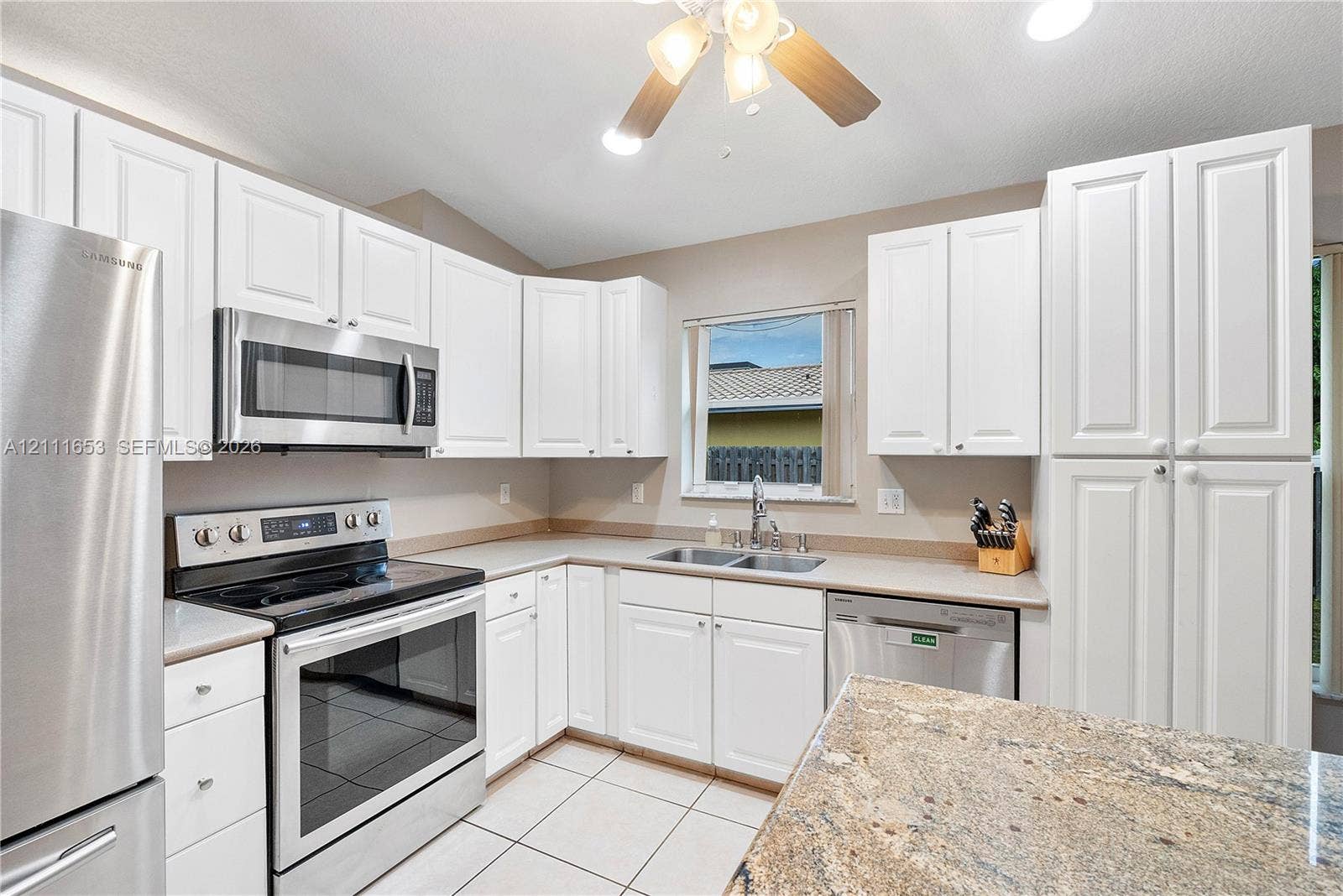 1042 NE 38th Street, Oakland Park, FL 33334 Kitchen featuring white cabinetry, stainless steel appliances, stone-surface countertops, and tile flooring