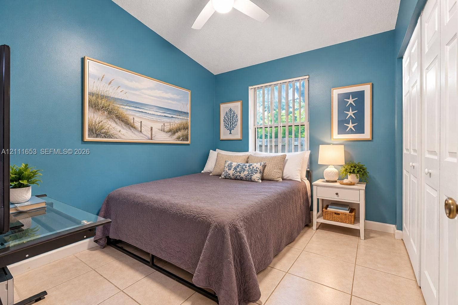 1042 NE 38th Street, Oakland Park, FL 33334 Bedroom 2 vaulted ceiling, ceramic tile flooring, vertical window blinds, and dual-panel closet doors
