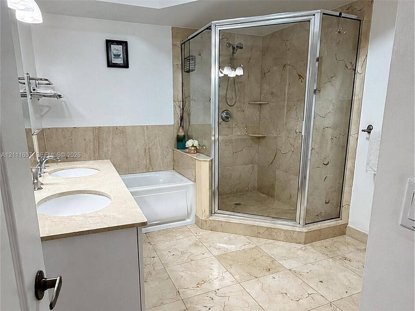 Dual-sink vanity with a stone countertop, stone tile flooring, a built-in bathtub, and a glass-enclosed corner shower with stone tile surround