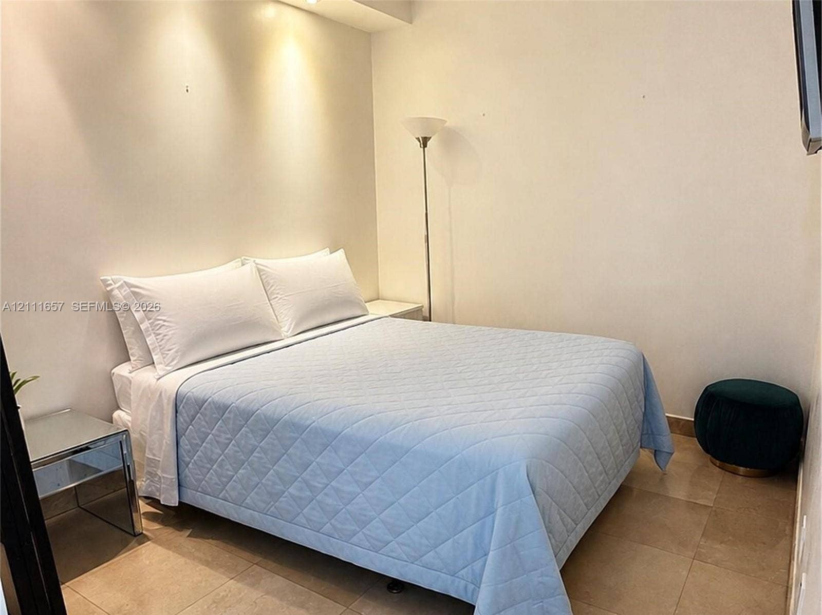 Neutral-toned tile flooring and recessed cove lighting with integrated spotlights