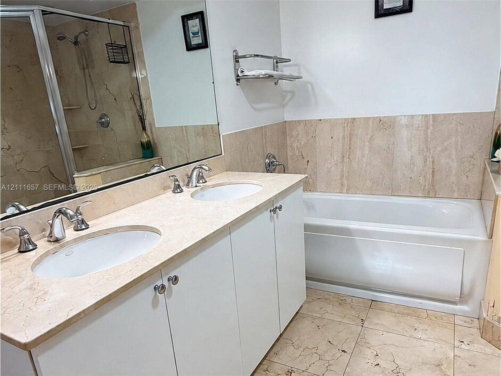 Dual-sink vanity with stone countertop, drop-in soaking tub with stone surround, tile flooring, wall-to-wall mirror, and glass-enclosed shower